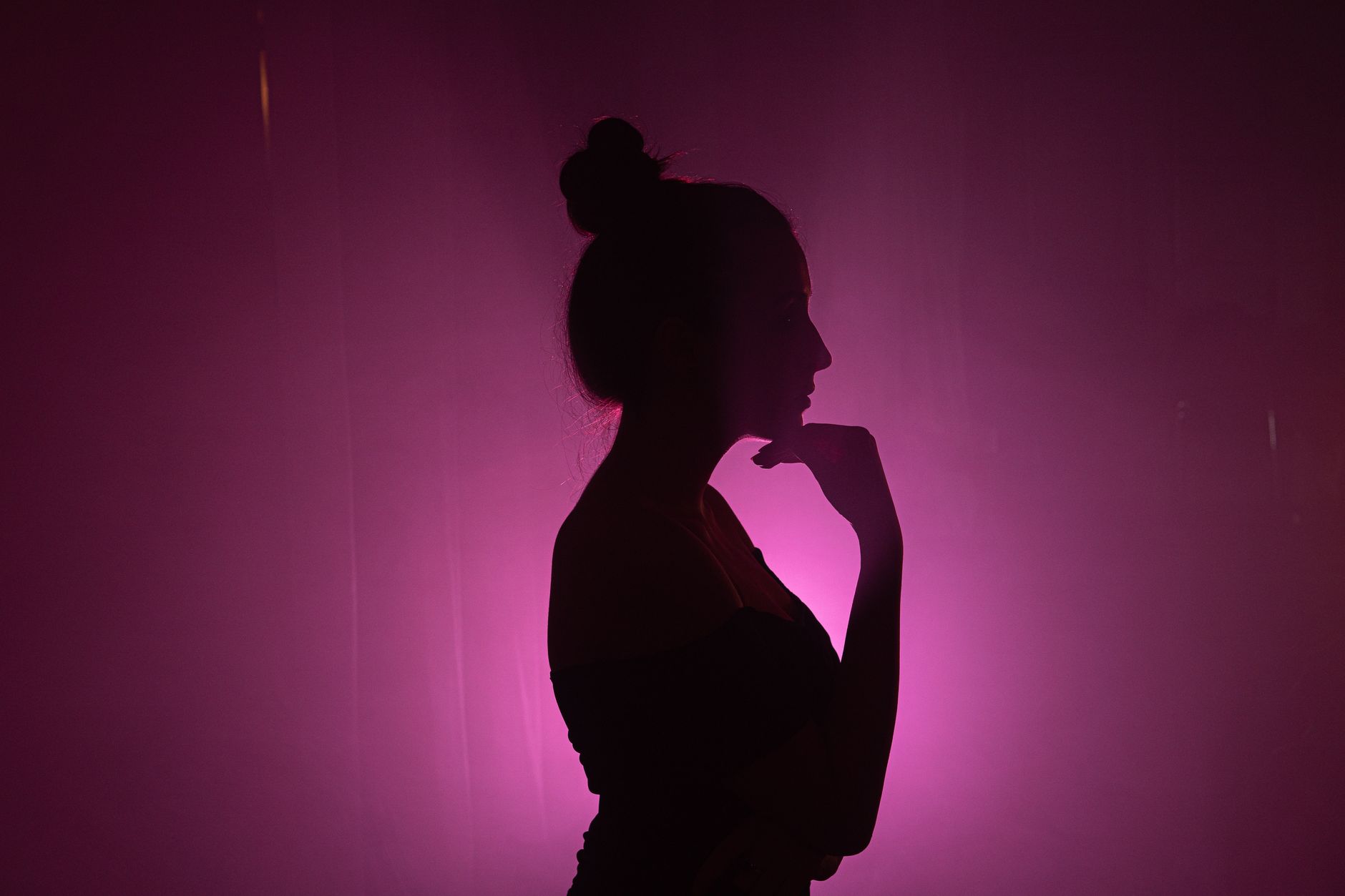 Silhouette artistica di una donna con capelli lunghi su sfondo rosa vivace