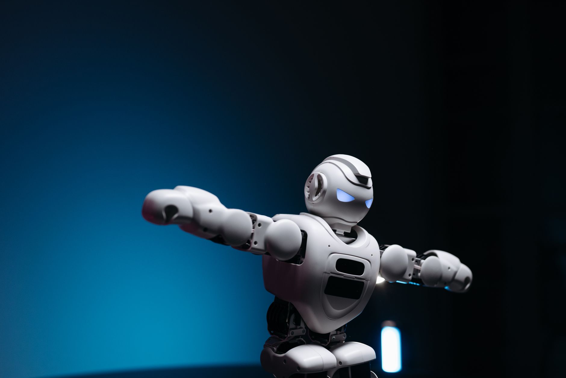 Primo piano di un robot giocattolo futuristico con occhi luminosi su sfondo blu, simbolo di innovazione